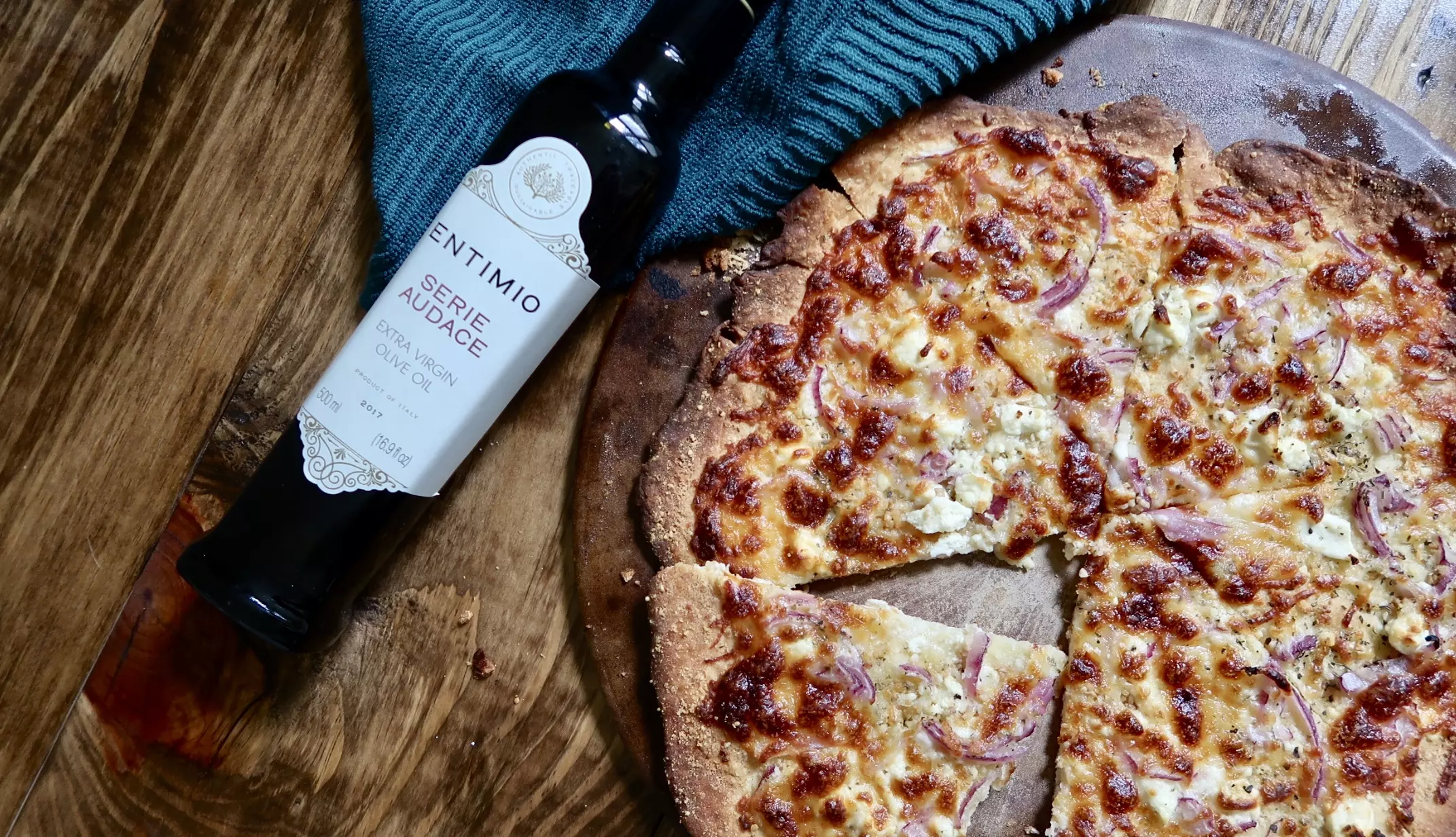 пицца с сыром, рядом бутылка оливкового масла