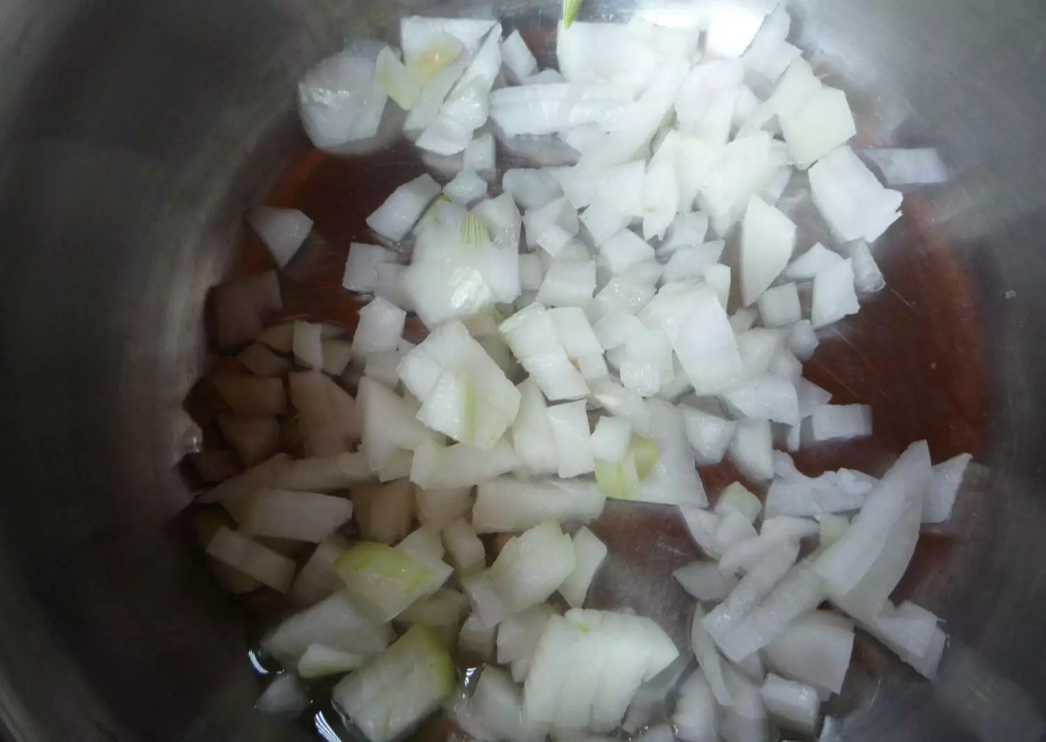 нарезанный кубиками лук в сковороде с растительным маслом