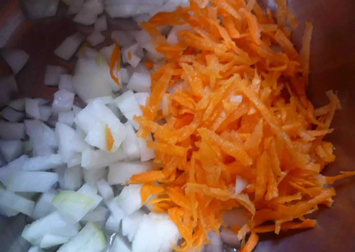 нарезанный репчатый лук и тертая морковь в сковороде