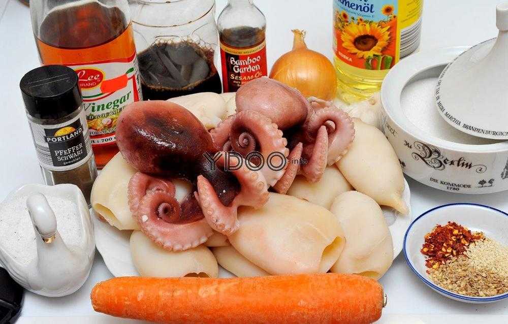 два осьминога, тушки кальмаров в тарелки и разнообразные специи на столе