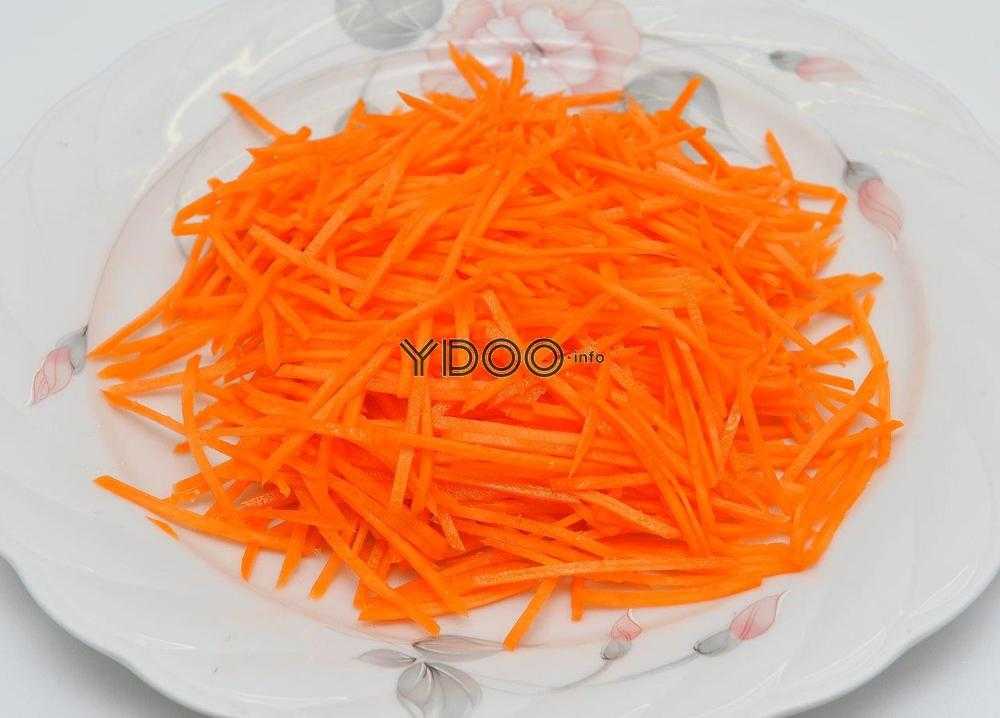 измельченная морковь на терке по-корейски в белой тарелке на столе