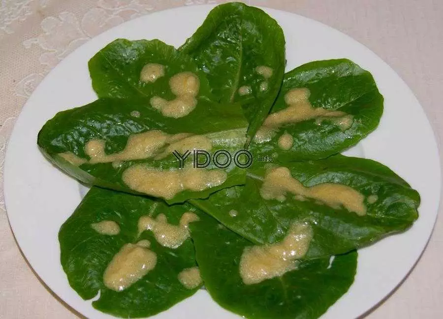 листья салата романо, плитые соусом, в тарелке