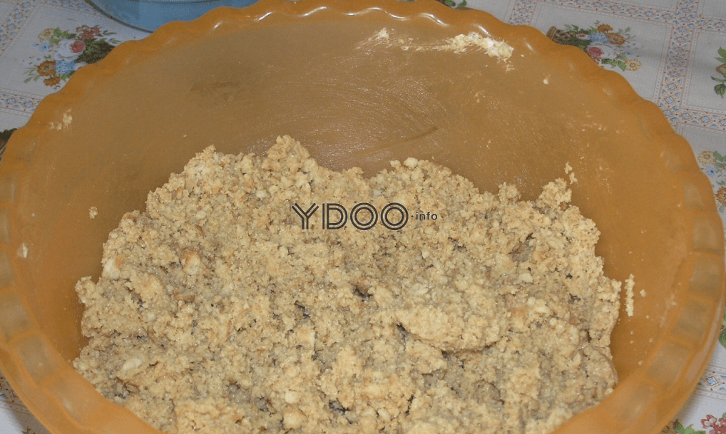 основа для пирожных из крошки из печенья и крема на основе сгущенки в глубокой пластиковой миске оранжевого цвета