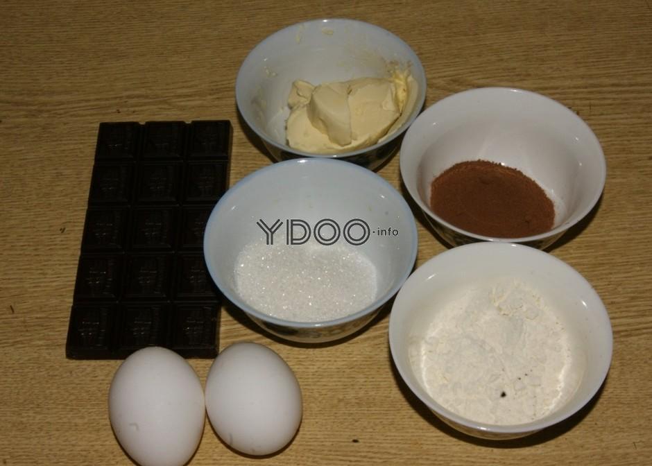 плитка шоколада на столе, рядом куриные яйца и пиалы со сливочным маслом, сахарным песком, какао, мукой