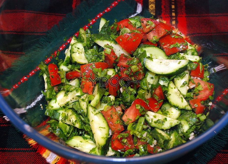 салат из огурцов, помидоров и зелени в стеклянной миске на столе, застеленном красно-черной клетчатой скатертью