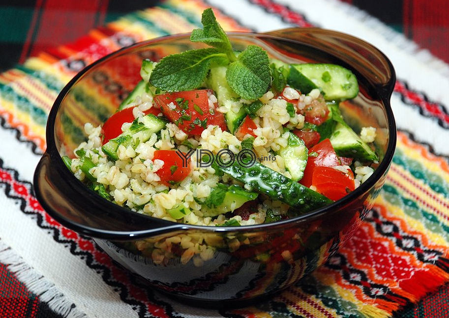 ливанский салат табуле с булгуром, огурцами, помидорами и зеенью в тарелочке на столе, застеленном красно-черной клетчатой скатертью