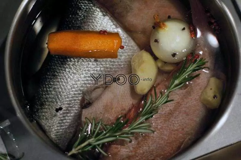 форель и морской окунь в кастрюле с водой и овощами (луком, морковью, имбирем), а также специями