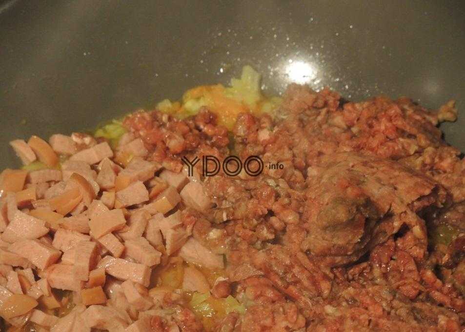 говяжий фарш и сосиски нарезанные кубиками в сковороде с жаренными луком и морковью