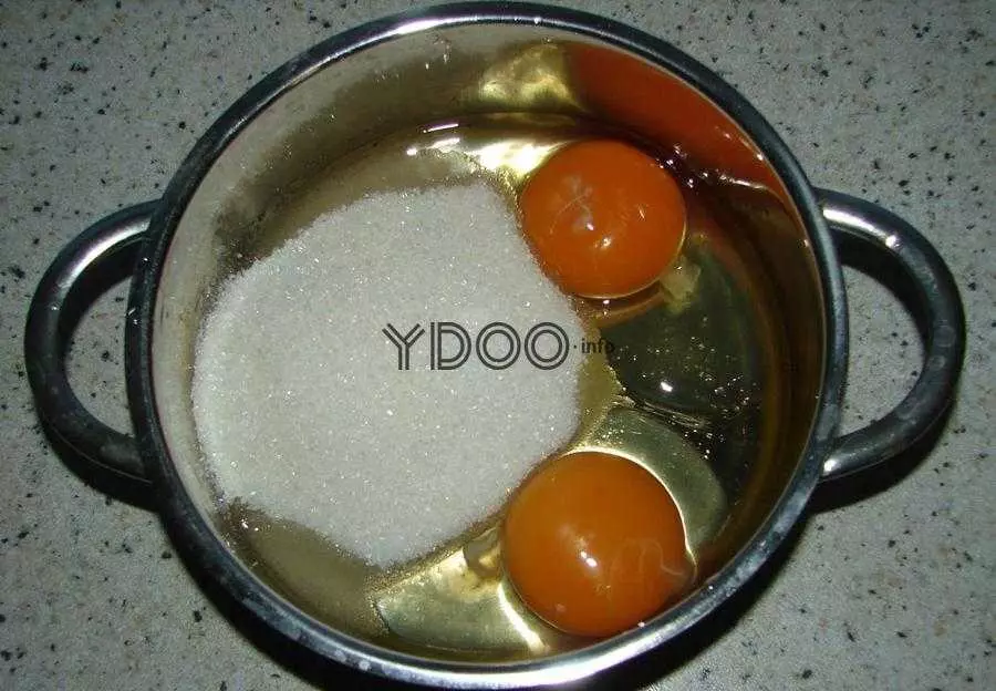 кастрюлька на столе с двумя вбитыми в нее куриными яйцами и сахарным песком