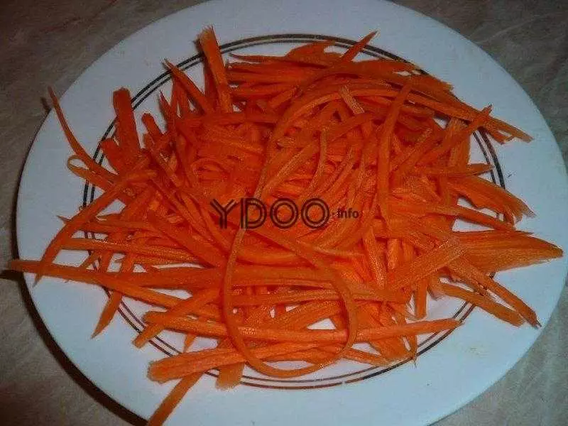 тертая морковь на белой тарелке на кухонном столе