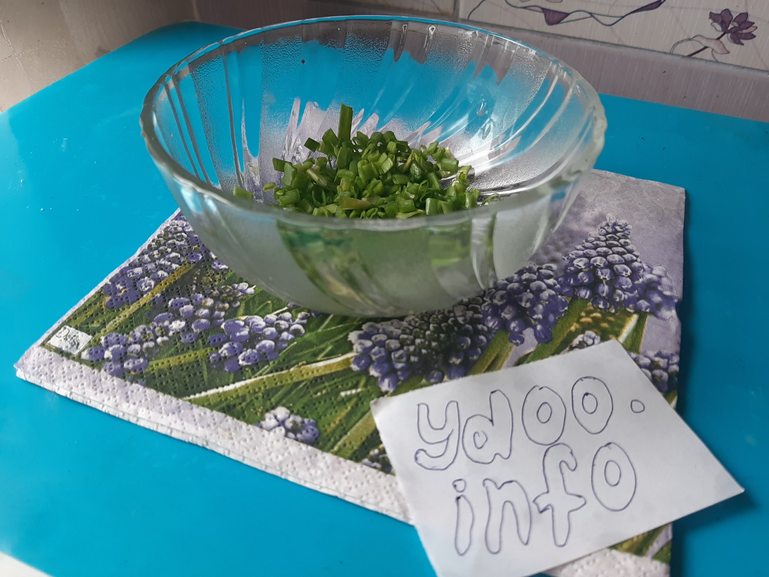 нарезанный зеленый лук в стеклянной салатнице на столе