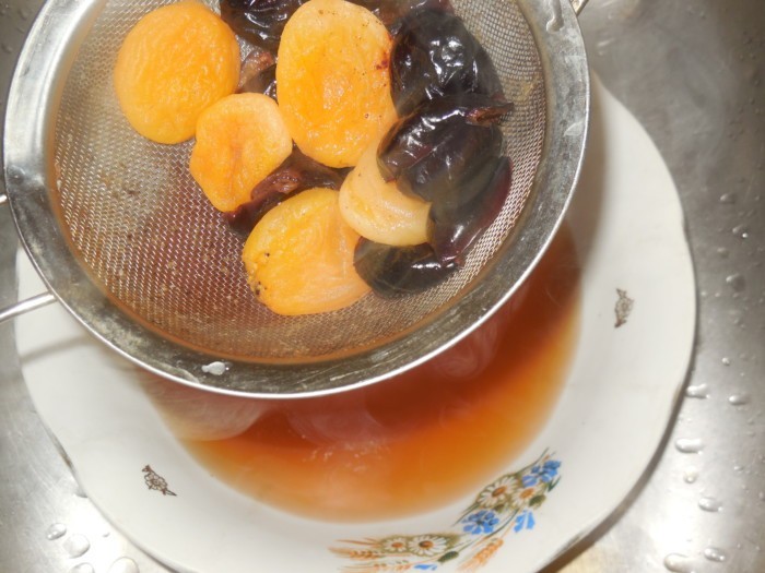 вареные чернослив и сушеный абрикос в сите над тарелкой с узваром