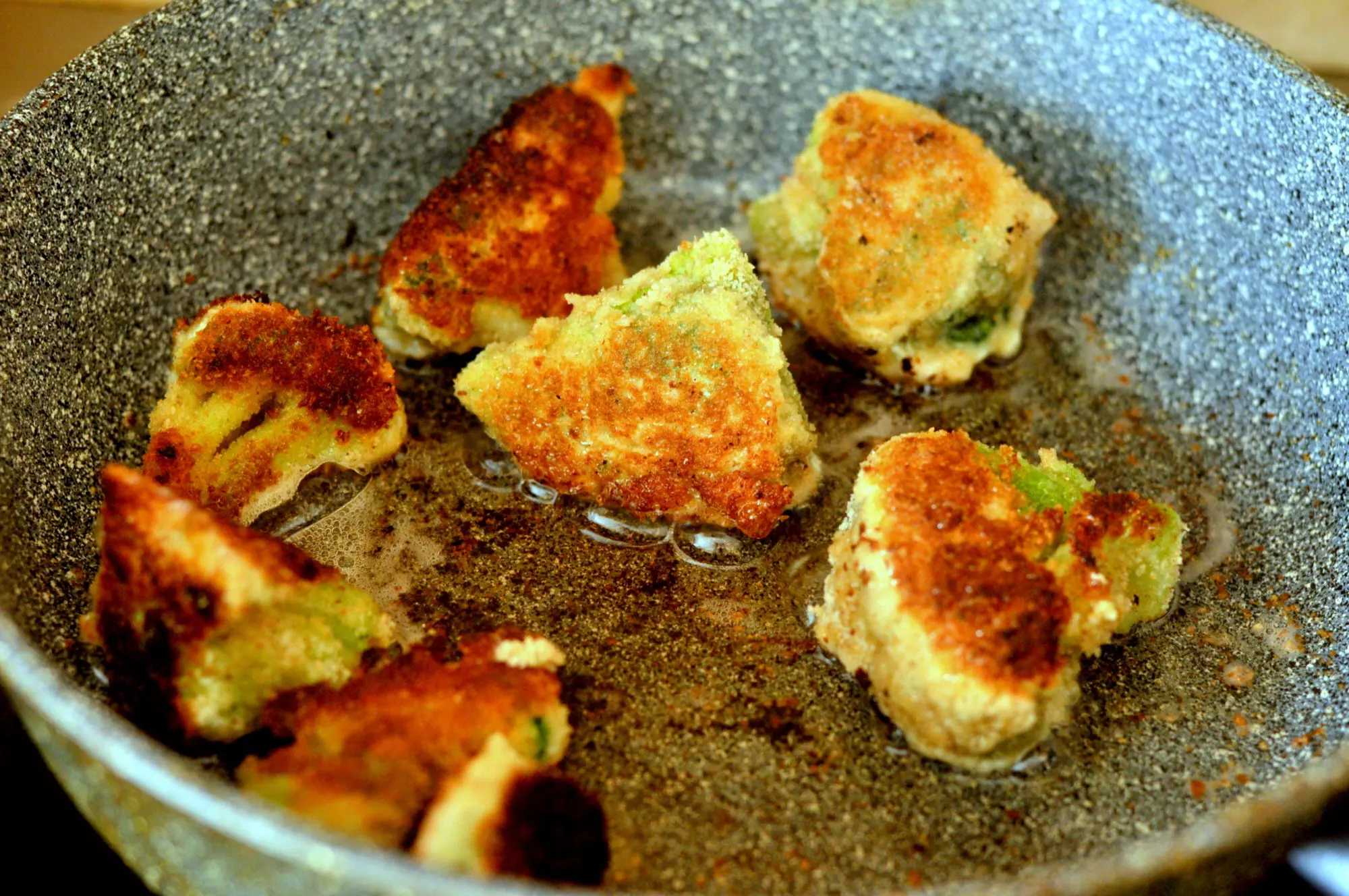 жареные брокколи в кляре в сковороде с маслом