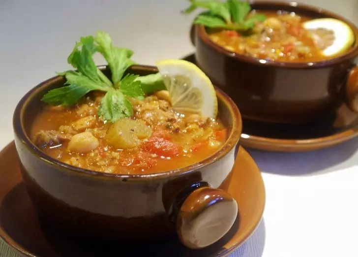 готовый марокканский суп в супницах на столе, украшенный зеленью и лимонами