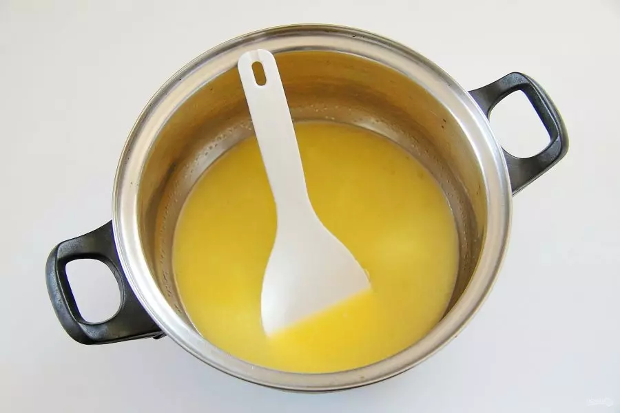 растопленное сливочное масло в кастрюле с ложкой на столе