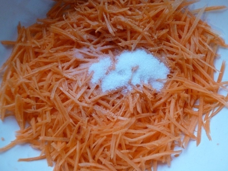 тертая сырая морковь, присыпанная сахаром, в белой миске