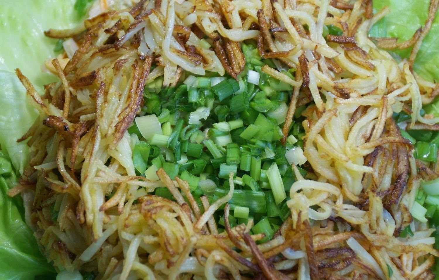 салат из рубленого зеленого лука и жареной картошки на листьях салата