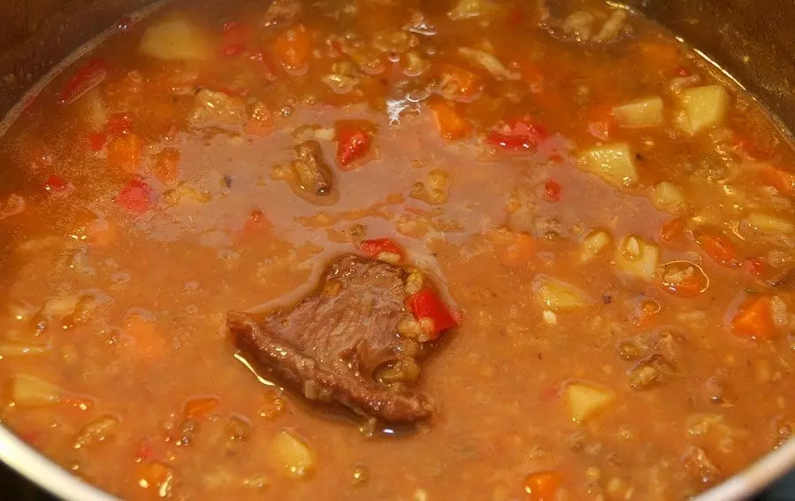 томатный суп с кусочками мяса, картофелем, красным сладким перцем, морковью и рисом в емкости