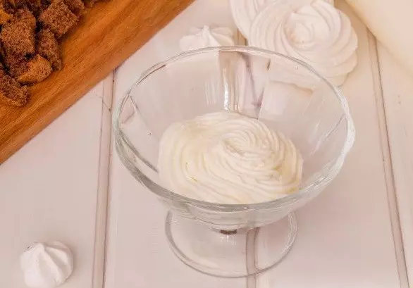 слоеный десерт из творожного крема в стеклянном стаканчике на столе
