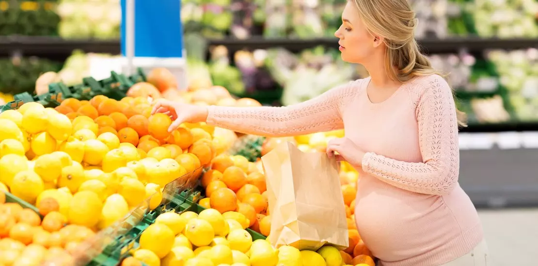 Беременным есть фрукты. Девушка с апельсинами. Девушка выбирает фрукты. Цитрусы для беременных.