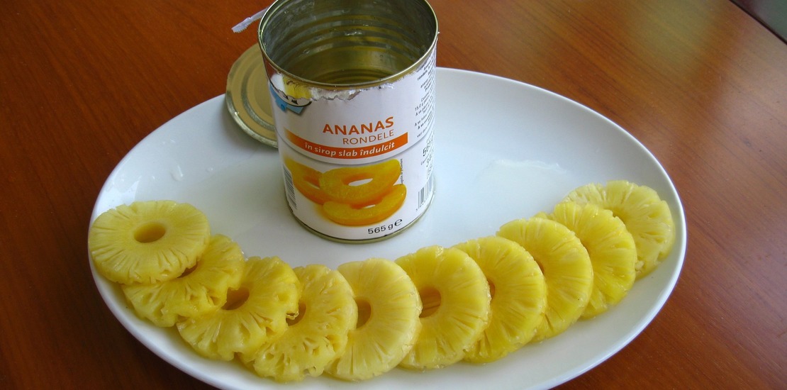 консервированные ананасы кольцами лежат на тарелке, рядом стоит банка