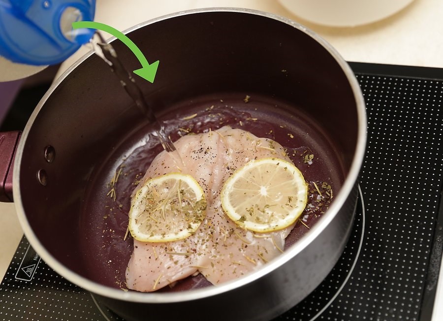 кусочки мяса со специями и дольками лимона, залитые водой, в сковороде